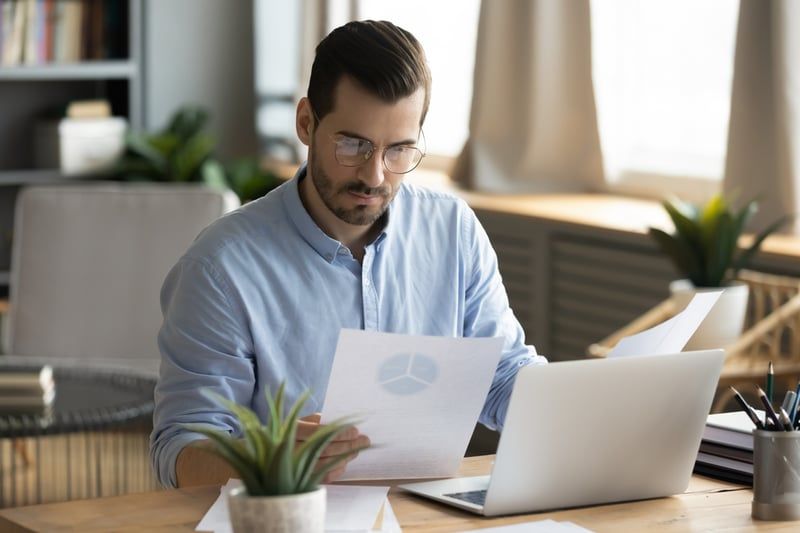 A consultant reviewing a report at his desk
